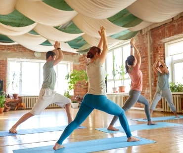 group of people doing yoga warrior pose at studio Naturheilpraxis Aachen